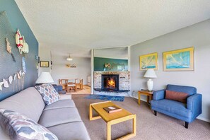 Un salon avec une cheminée, un canapé, un fauteuil bleu et une table basse.