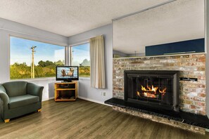Ein Wohnzimmer mit Kamin, Fernseher und einer Couch.