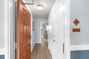 Un couloir avec une porte en bois, une porte blanche et une plaque sur le mur indiquant le numéro de la pièce : 312.