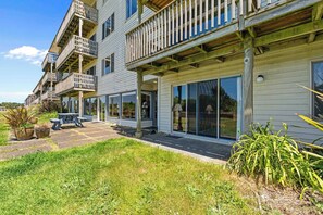 A multi-story building with balconies, large windows, and a covered patio area. - Pet Friendly Suite with Patio - Pool and Hot Tub! (Ocean Shores)