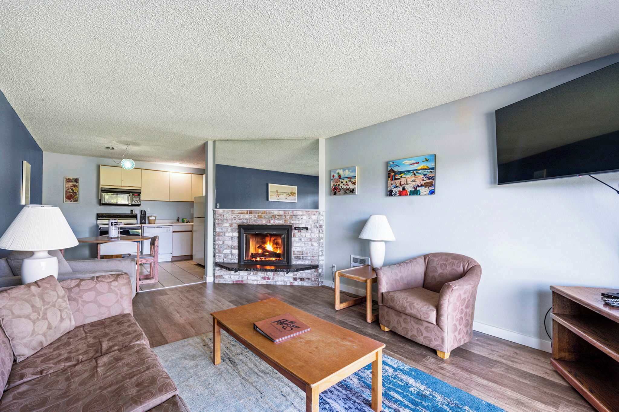 A living room with a fireplace, sofa, coffee table, and a TV mounted on the wall.
