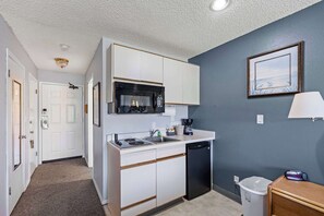 A compact kitchen with white cabinets, a microwave, a sink, and a dishwasher. - King Bed Studio with Kitchenette - Pool & Hot Tub! (Ocean Shores)