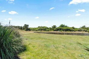 A grassy field with a wooden fence and trees in the background. - King Bed Studio with Kitchenette - Pool & Hot Tub! (Ocean Shores)