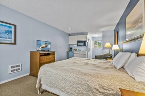 Ein Hotelzimmer mit Bett, Fernseher, Küchenzeile und Bad.