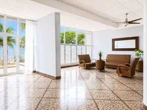 A spacious room with a large window, a ceiling fan, and a sofa. - Corner For 2 BEAUTIFUL OCEAN VIEW Pool Beach Parking CONDADO (San Juan)