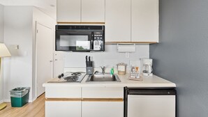 Uma cozinha compacta com micro-ondas, fogão, pia e cafeteira.
