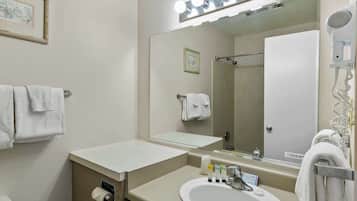 Un baño con lavamanos, espejo, perchero para toallas y un secador de pelo.