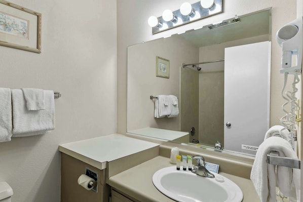 Un baño con lavamanos, espejo, perchero para toallas y un secador de pelo.