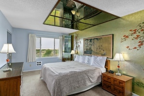 A bedroom with a bed, bedside tables, a window, and a painting on the wall. - Ocean View Penthouse Suite - Pet-Friendly - Pool and Hot Tub! (Ocean Shores)