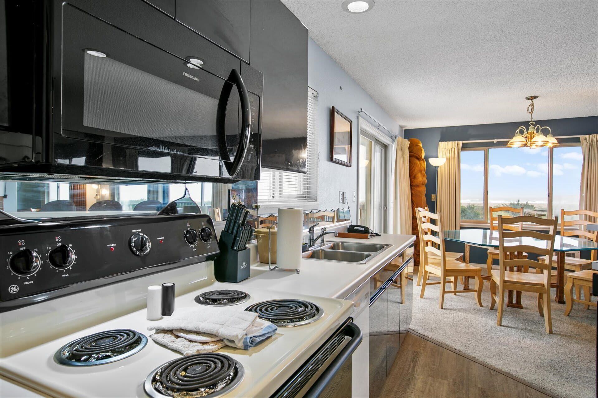 Una cocina moderna con estufa, horno y microondas. Hay un comedor con mesa y sillas.