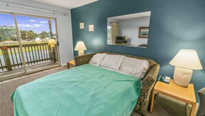 Quarto de hotel com uma cama, duas mesas de cabeceira com abajures, um espelho e vista para o exterior.