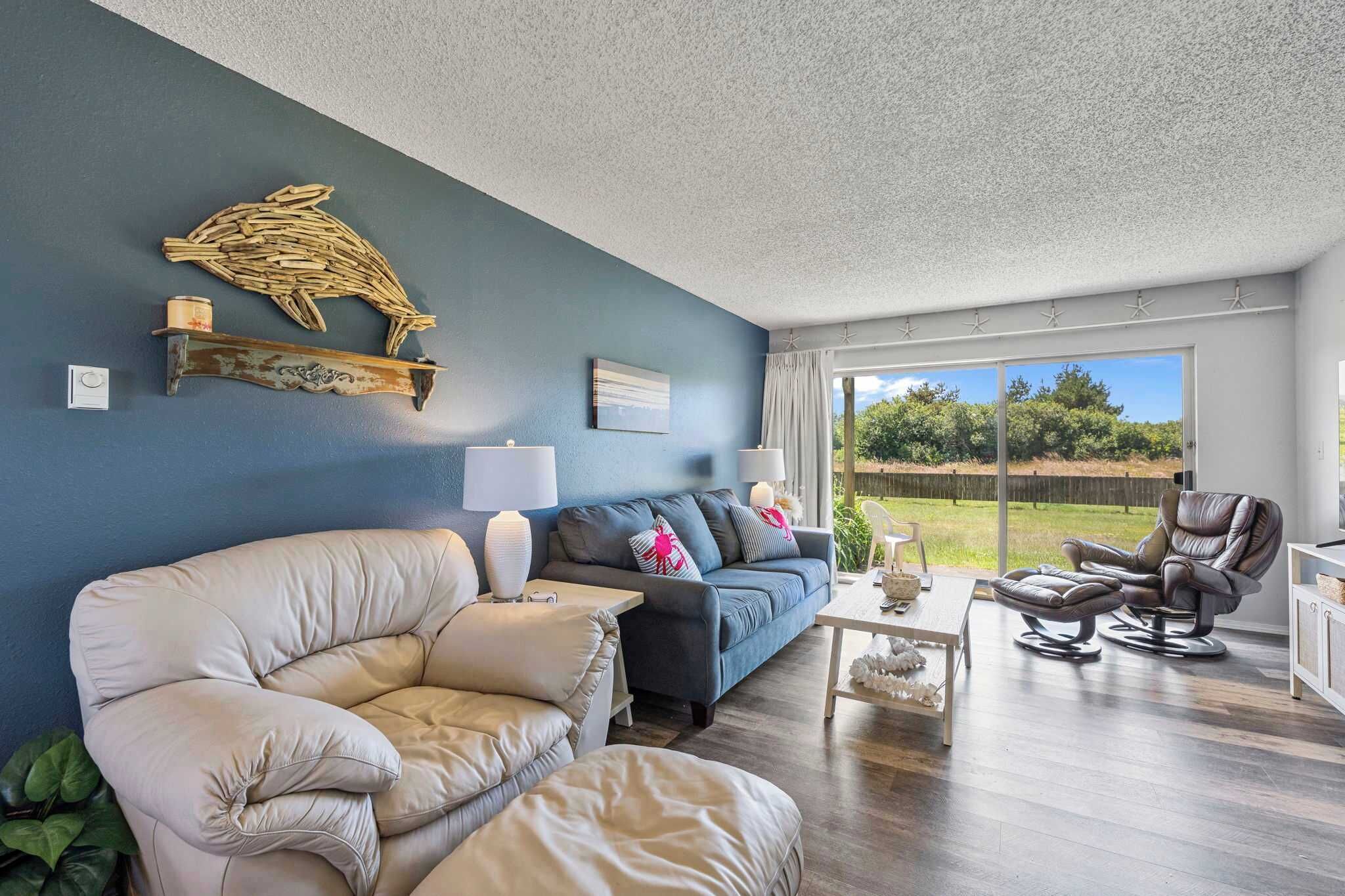 Una sala de estar con sofá, sillón y una butaca, con vistas al exterior.