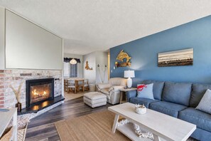 Ein Wohnzimmer mit Kamin, blauer Wand, einer Couch und einem Essbereich.