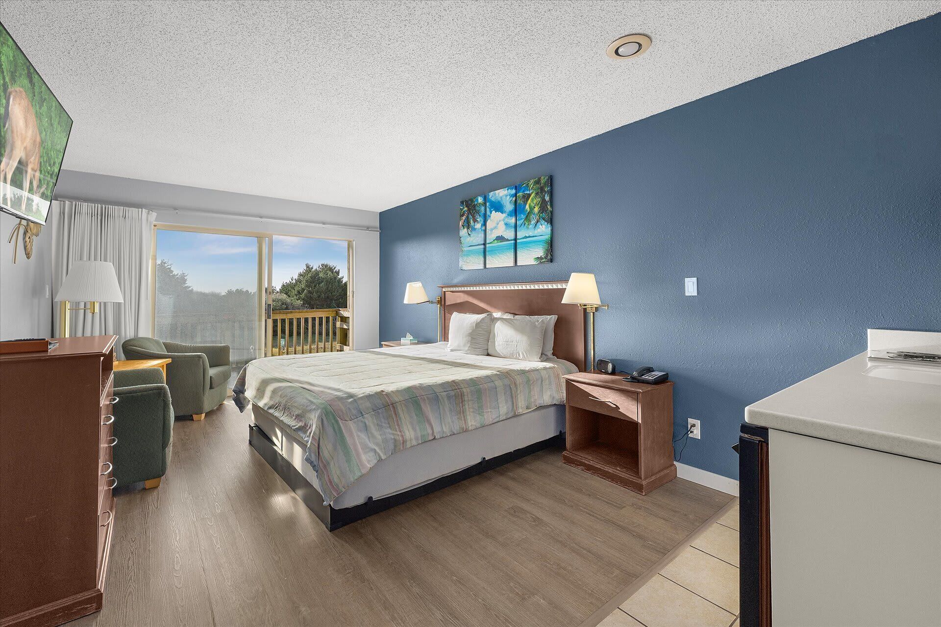 A bedroom with a bed, bedside tables, a desk, a chair, a window with a view, and a painting on the wall.