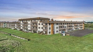 Un hotel de varios pisos con balcones, estacionamiento y un área con césped.