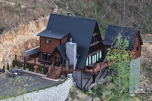 Eine große, mehrstöckige Holzhütte mit Steinfundament, steilem Dach und einer Holzterrasse.