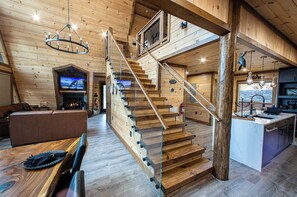 Ein Holzinnenraum mit Treppe, einem Wohnbereich mit Kamin und einer Küche.