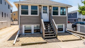 A two-story house with a front staircase, a front door, and a small porch area. - 4BR Beach Block Home w/ Washer-Dryer, Free Parking (Seaside Heights)