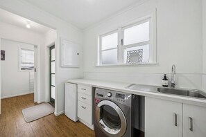 Eine kompakte Küche mit integriertem Waschmaschine, Spüle und Fenster über der Arbeitsplatte.