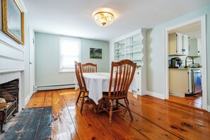 A dining area with a wooden table and chairs, a chandelier, and a kitchen in the background. - Charming 3-bedroom apartment with AC in East Greenwich (East Greenwich)