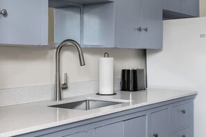 A kitchen with a stainless steel sink, a paper towel dispenser, and a toaster on the counter. - 2 Bedroom + Pull out Sofa | Min to UofC (Calgary)