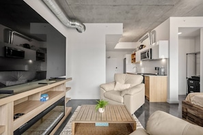 A modern living room with a sofa, a coffee table, and a TV. - `The Cedar` | Mins to Stampede | Patio Fire-pit (Calgary)