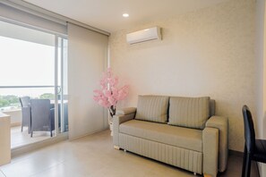 A modern living room with a sofa, a chair, a potted plant, and a sliding glass door leading to an outdoor area. - Modern Oceanfront Loft and Beach | Santa Marta (Santa Marta)