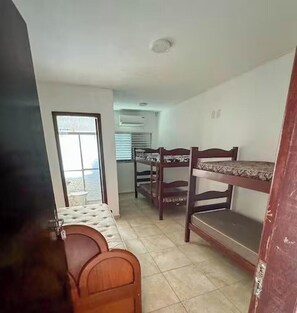 Quarto com beliches, janela e porta.