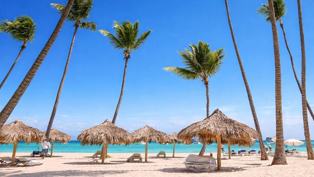 A beach with palm trees, thatched umbrellas, and lounge chairs. - El mar te Llama · 2BR Los Corales (Punta Cana)