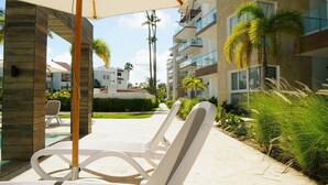 A resort with outdoor seating, palm trees, and modern buildings. - El mar te Llama · 2BR Los Corales (Punta Cana)