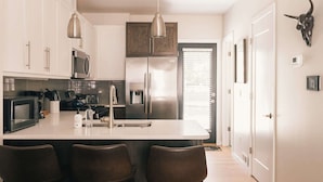 A modern kitchen with white cabinets, stainless steel appliances, and a central island with bar stools. - The Honeysuckle Homestead | Georgetown Living (Georgetown)