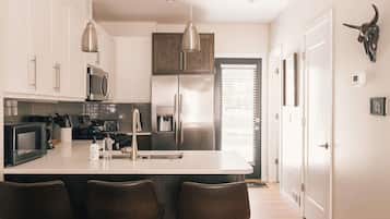 A modern kitchen with white cabinets, stainless steel appliances, and a central island with bar stools.