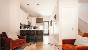 A modern living room with a glass coffee table, two sofas, and a kitchen in the background. - The Honeysuckle Homestead | Georgetown Living (Georgetown)
