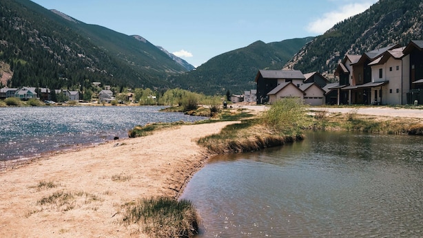 A lakeside hotel with multiple buildings, a river, and mountains in the background. - The Honeysuckle Homestead | Georgetown Living (Georgetown)