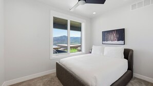 Un dormitorio con un ventanal, una cama y un cuadro en la pared.
