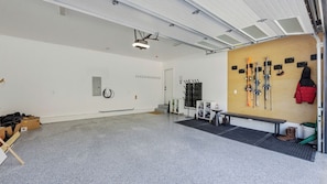 Amplio espacio interior con techo alto, un proyector montado, un esquí y un banco.