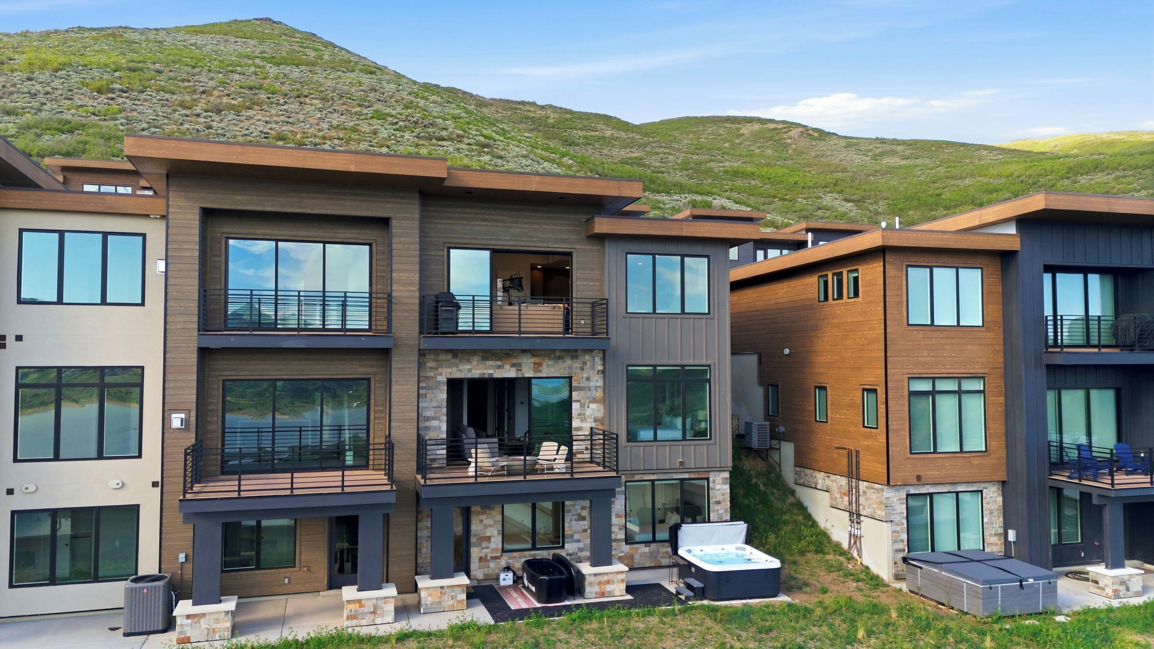 A multi-story residential building with balconies, large windows, and a hot tub in the outdoor area.