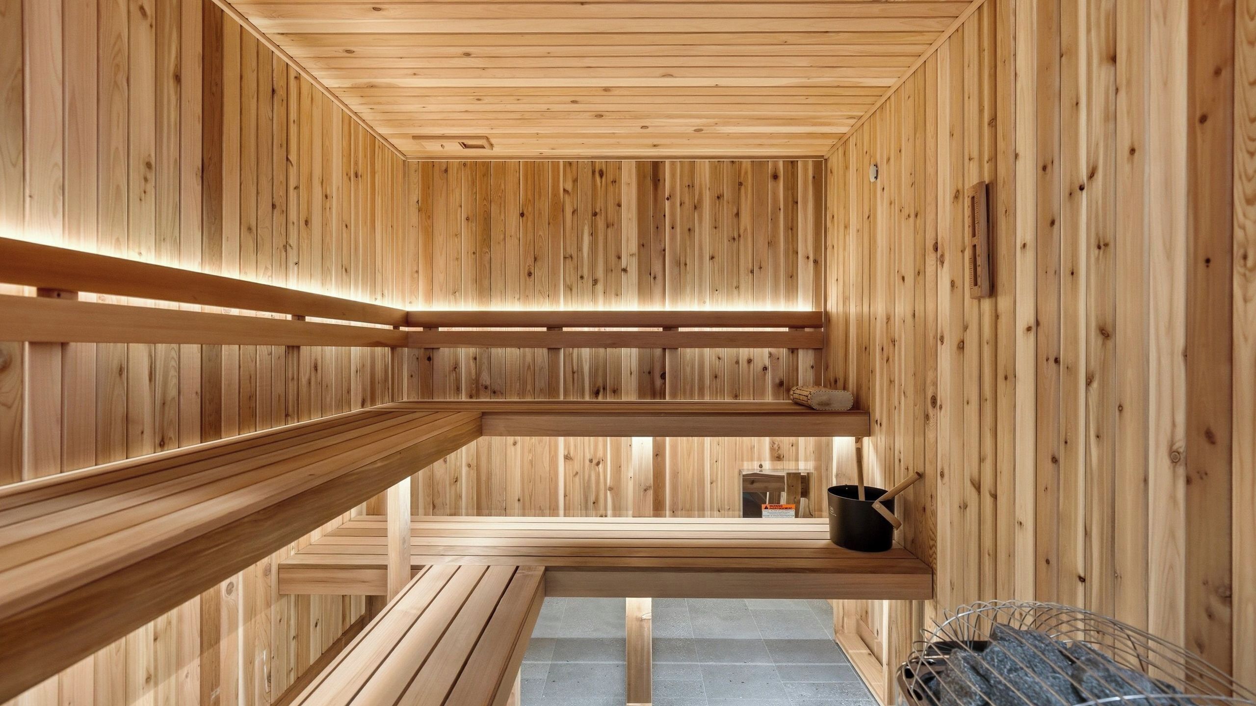A sauna with wooden walls and benches, a window, and a towel rack.