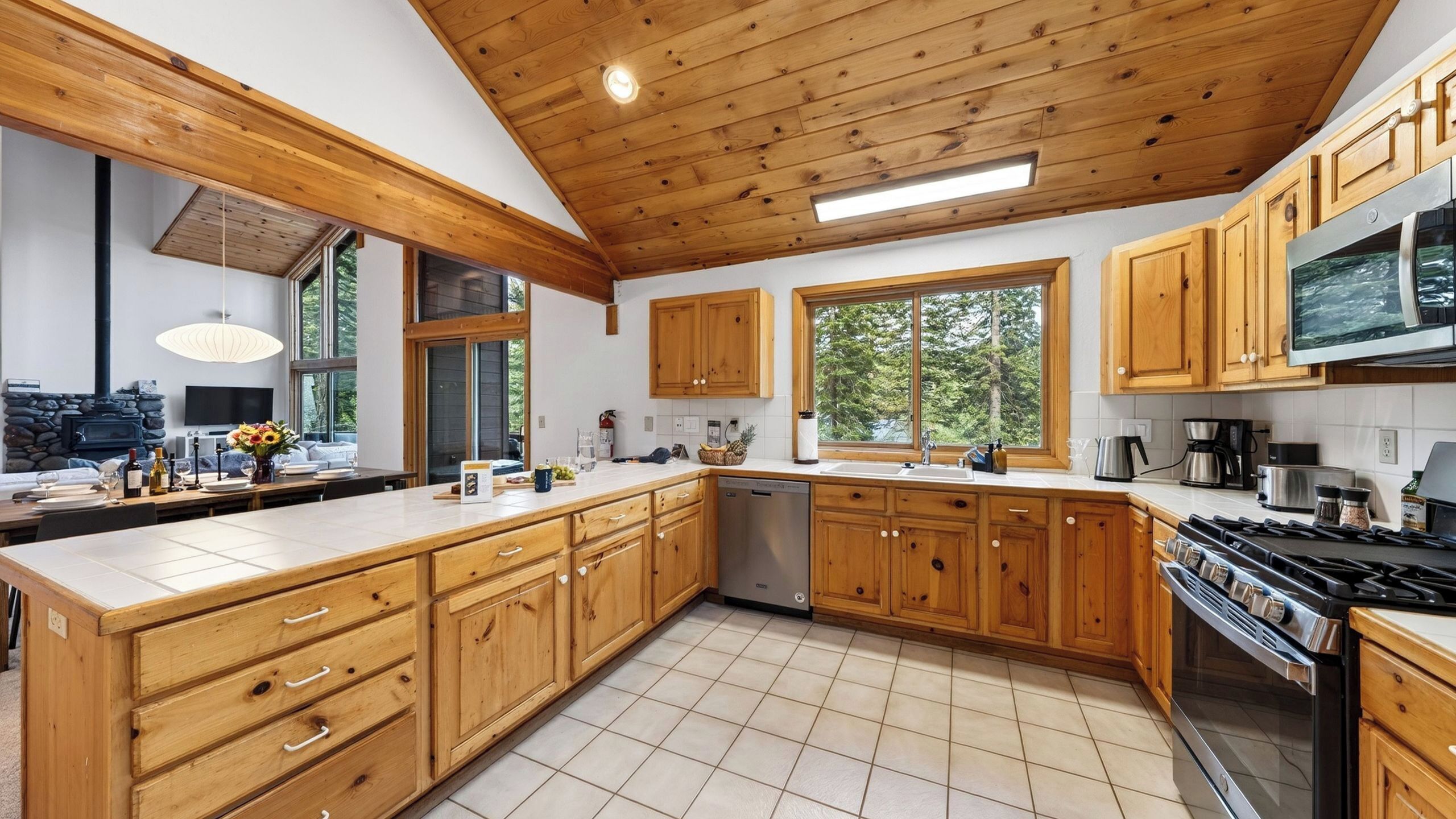 Eine moderne Küche mit Holzschränken, einer großen Kochinsel und einem eingebauten Backofen.