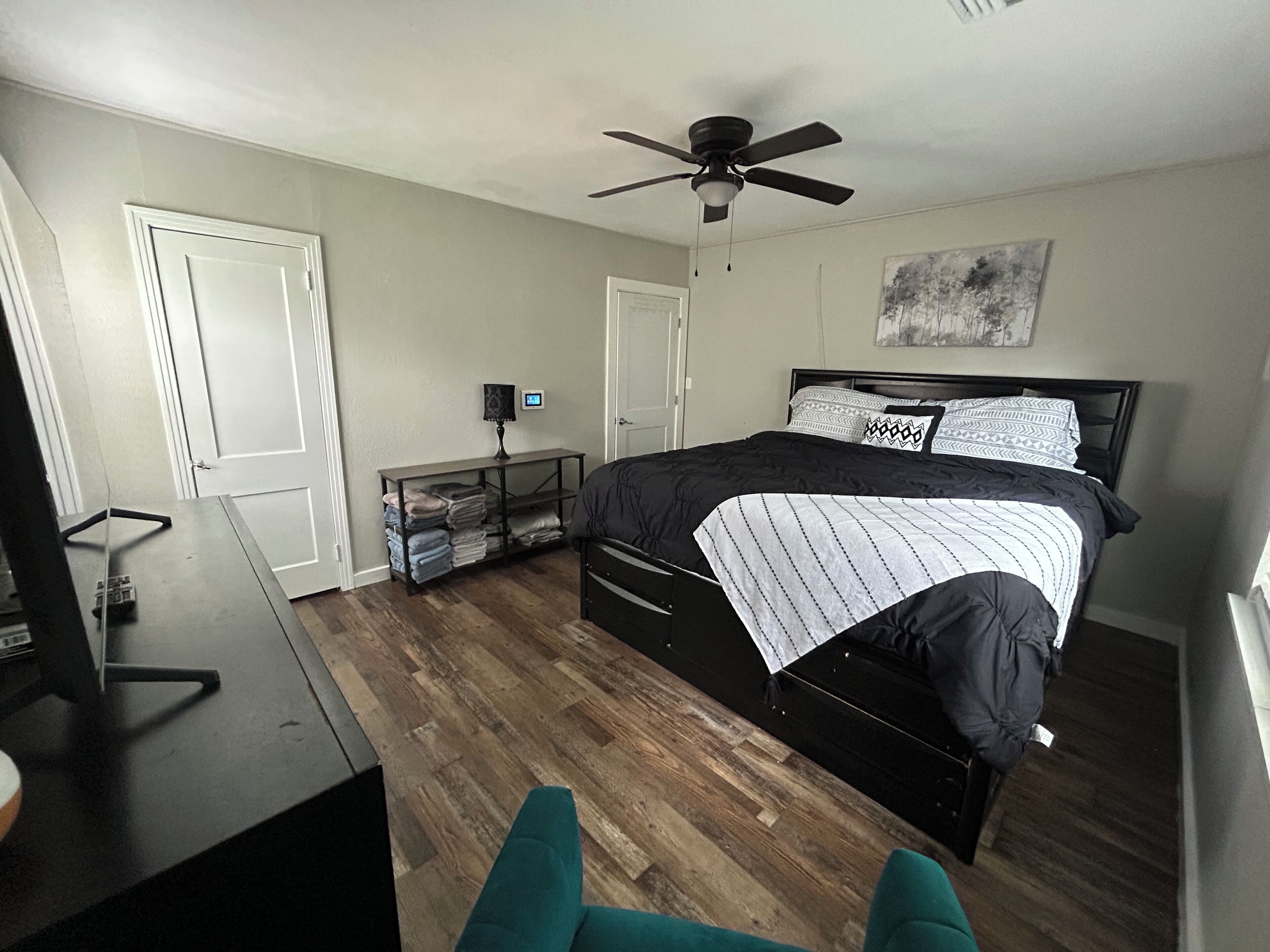 Une chambre à coucher comprenant un lit, un bureau, une chaise, un ventilateur de plafond et une lampe fixée au mur.