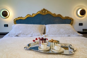 A bed with a decorative headboard, a tray with cups and a mug, and a small container of cookies.