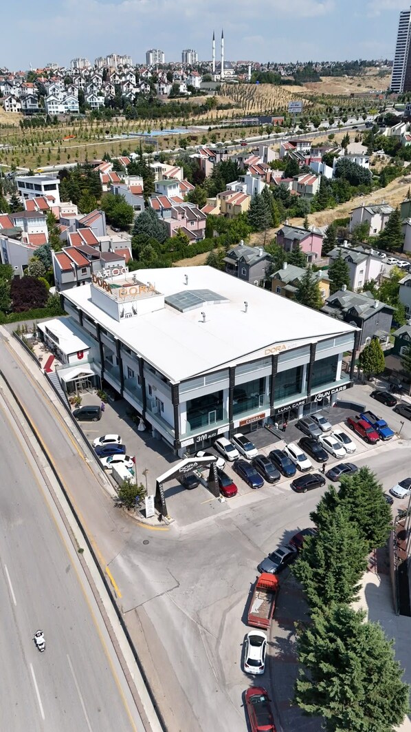 A multi-story building with a flat roof, surrounded by parked cars and residential houses.