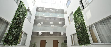 A modern interior with a central atrium, large windows, and hanging spherical light fixtures.