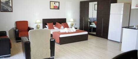 Una habitación de hotel con una cama, un escritorio, una silla, un armario y un refrigerador.