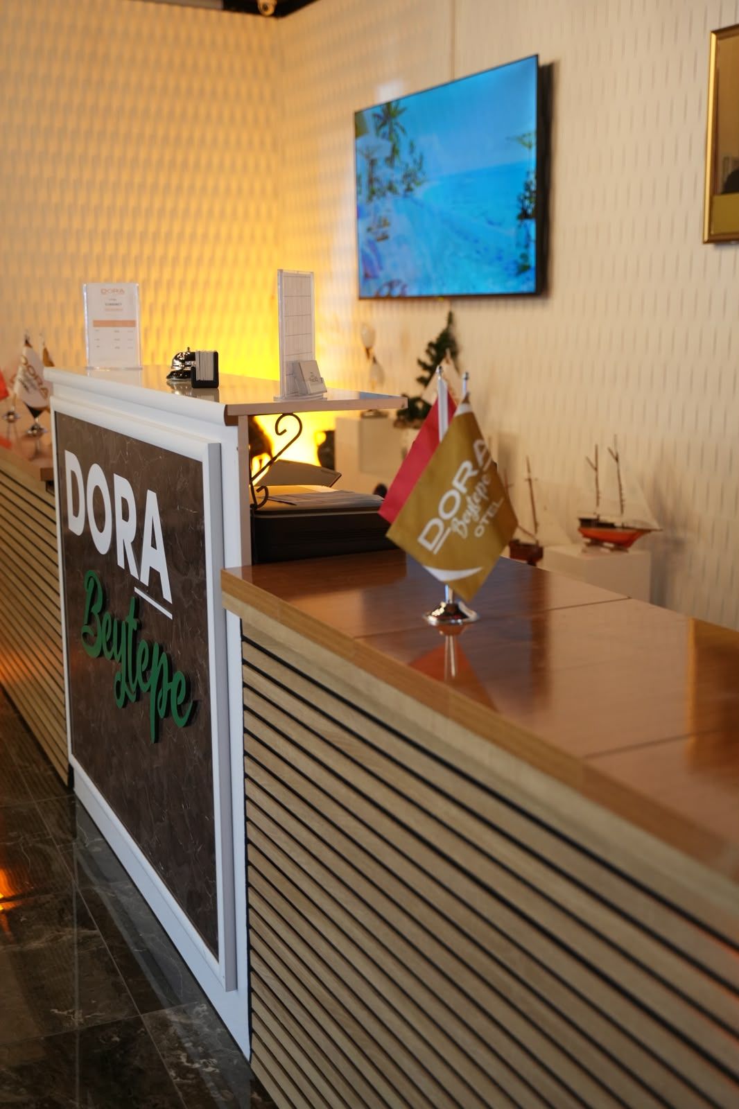 Una mesa de recepción con un letrero que dice 'DORA Beyerspe' y un pequeño modelo de barco en la barra.