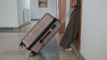 Una persona tira de una maleta con ruedas por un pasillo con piso de baldosas y una puerta a la derecha.
