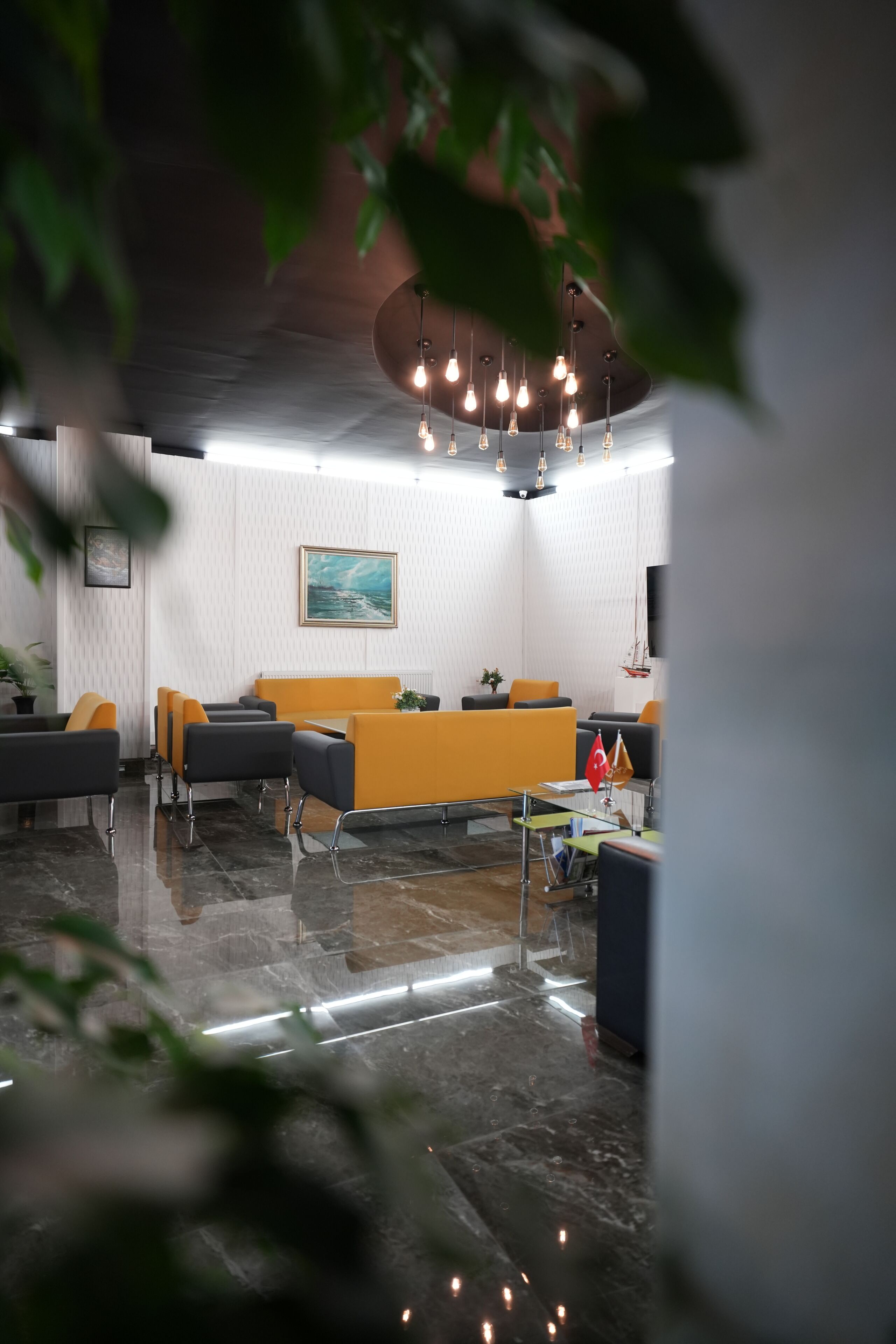 Un hall d’entrée moderne avec un comptoir d’accueil, un espace salon et un tableau accroché au mur.