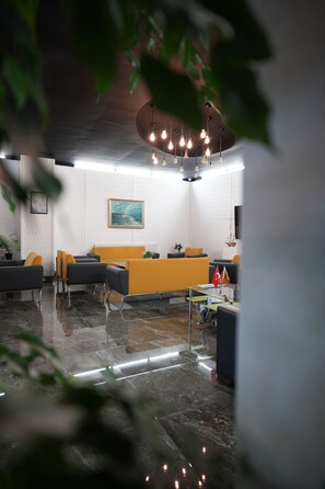 A modern lobby with a reception desk, seating area, and a painting on the wall. - DORA BEYTEPE HOTEL (Ankara)
