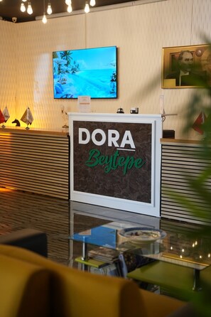 A reception area with a sign reading 'DORA Boutique' and a television displaying a snowy landscape.