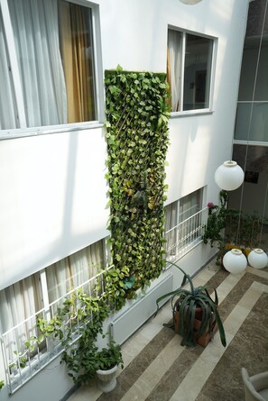 A modern apartment with a vertical garden, potted plants, and a tiled floor.